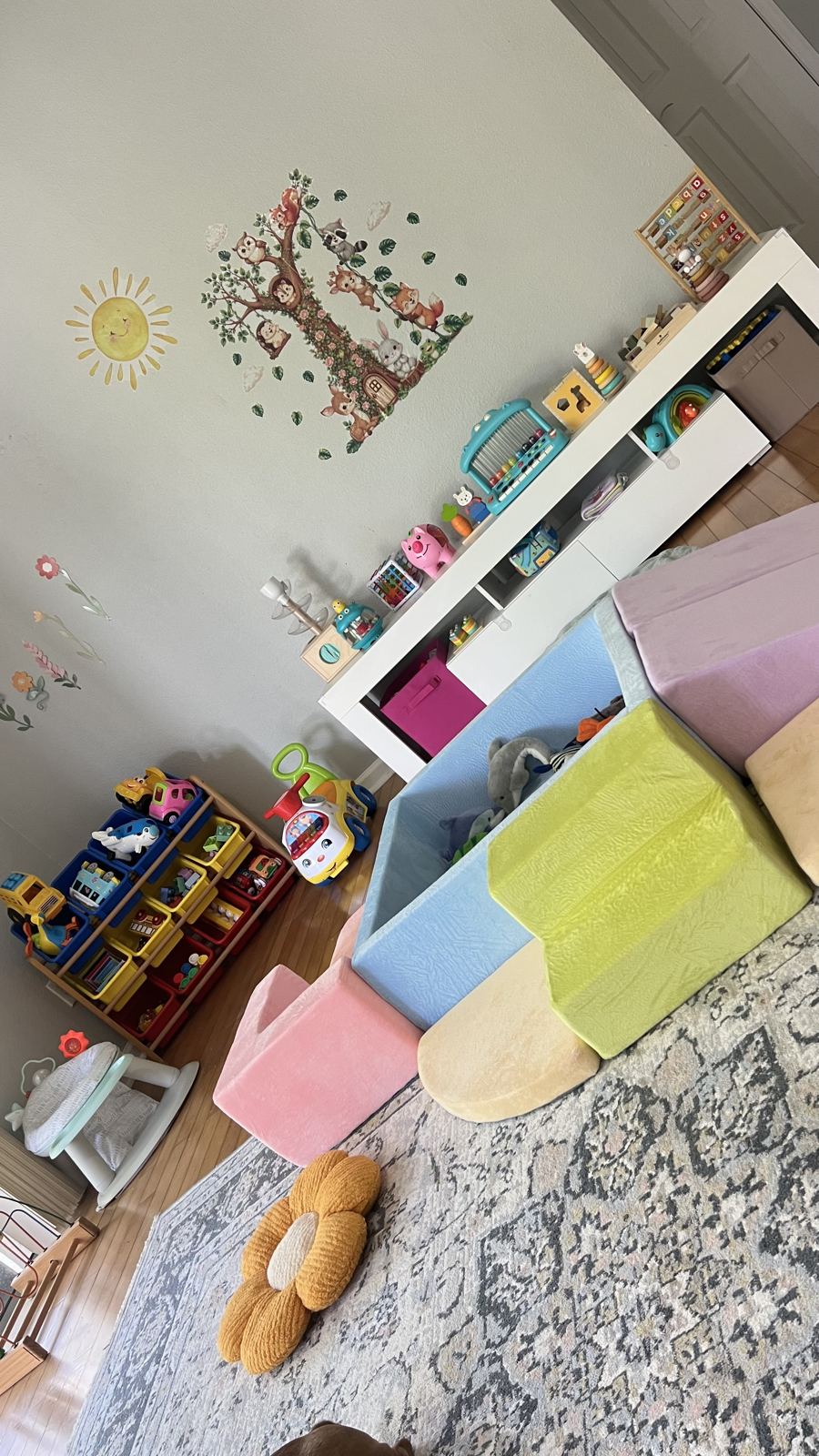 Infant play area with soft foam climbing shapes and a woodland wall mural