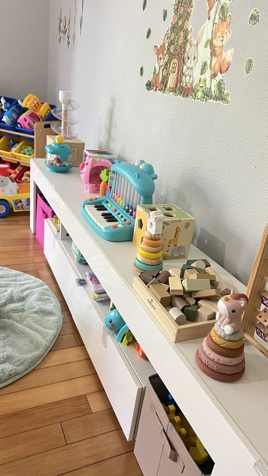 Low open shelf with wooden stacking toys, blocks, and a play piano within reach